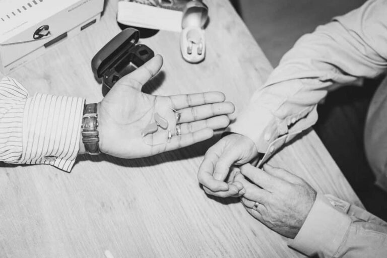 Man handing hearing aid to patient