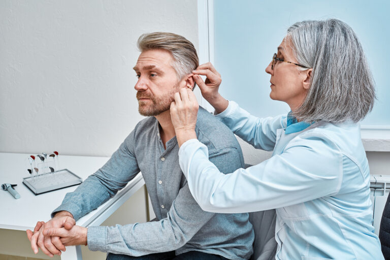 Experienced Female Doctor Fitting Intra-the-ear Hearing Aid Into