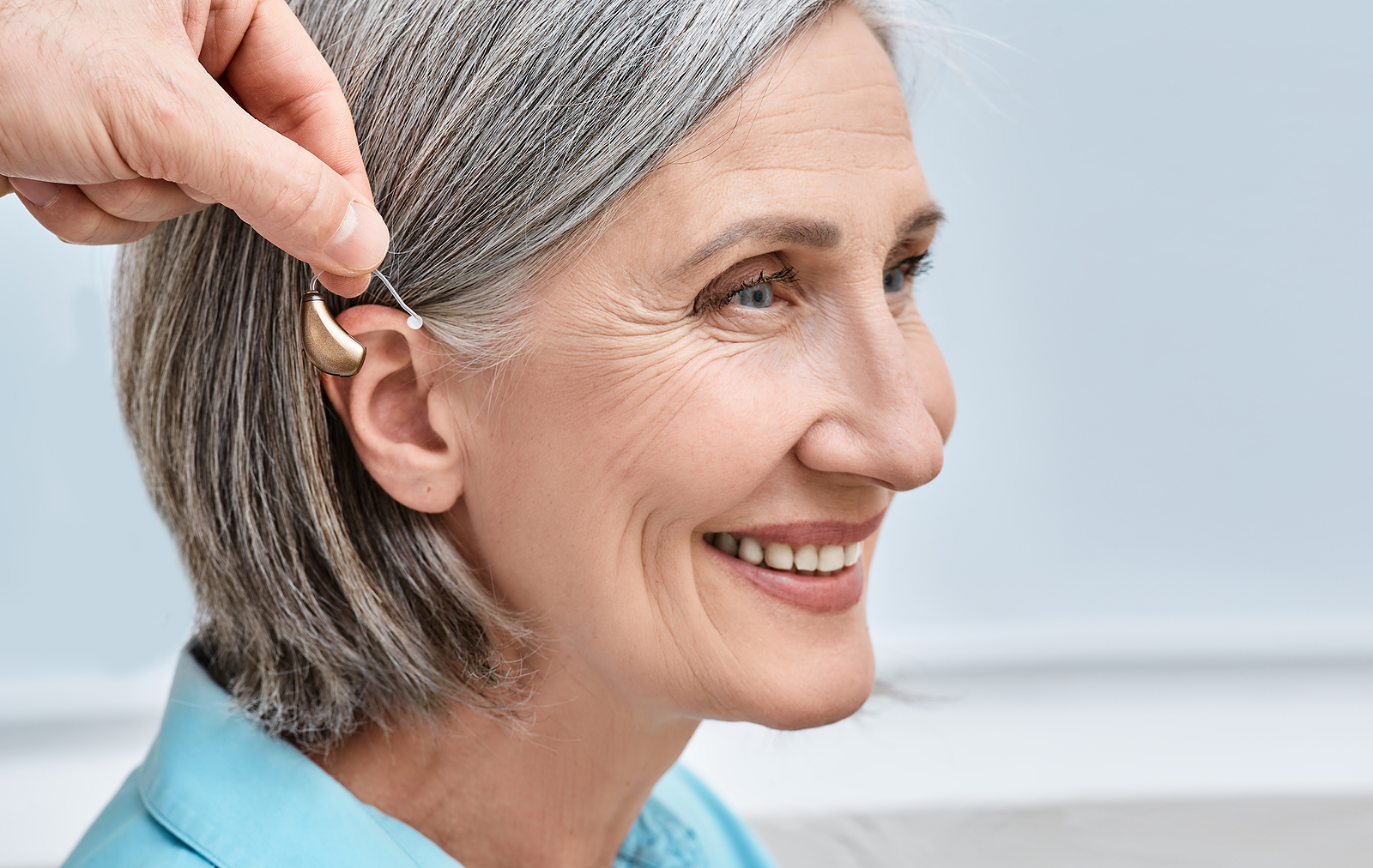 Close-up Of Hearing Aid Near Senior Female Patients Ear At Audio